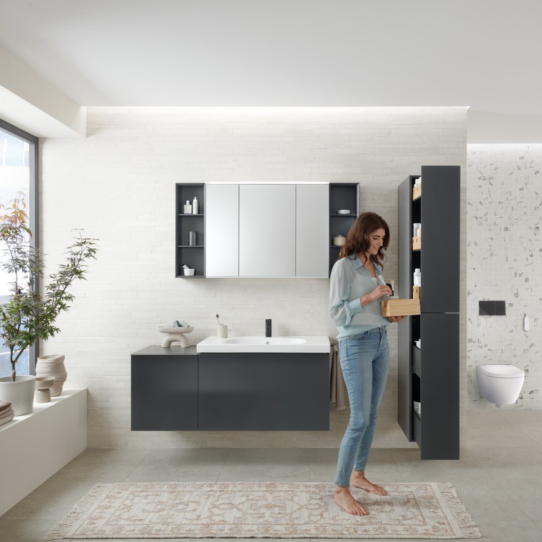 Woman opens tall cabinet with lots of storage space in bathroom with Geberit Acanto bathroom furniture Woman opens tall cabinet with lots of storage space in bathroom with Geberit Acanto bathroom furniture