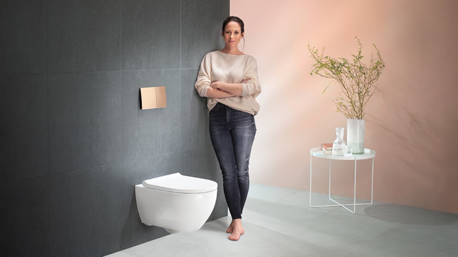 一位女士站在她的 Geberit Acanto 艾珈座便器旁,面露满意 一位女士站在她的 Geberit Acanto 艾珈座便器旁,面露满意